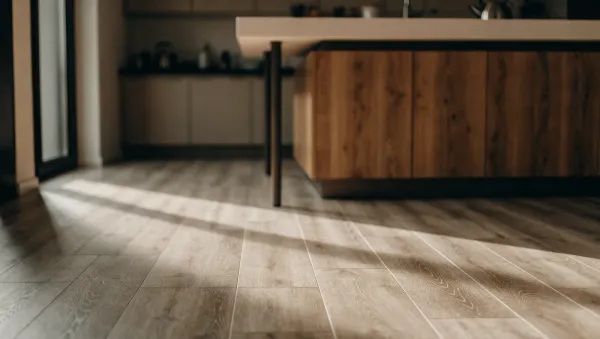 Lyst køkken med gennemgående vinylgulv i træ-look foran en køkkenø, med fokus på gulvets overflade og samlinger